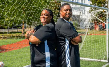 Danielle and Danny Johnson pose back to back with their arms crossed.