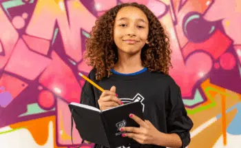 Poet-Athlete Carter Sewell smiles and poses with a notebook and pencil